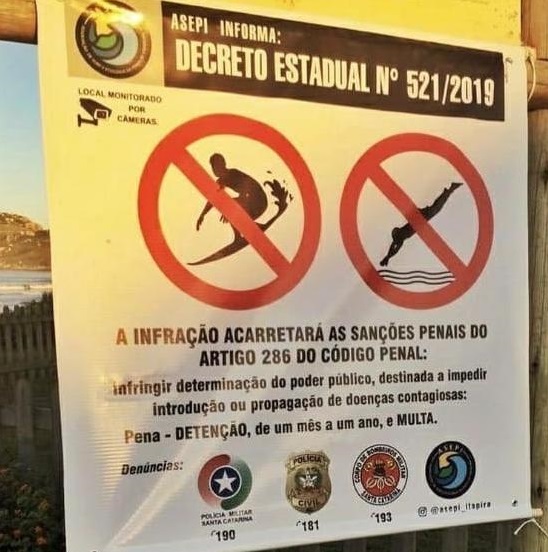 Placa proibindo o surfe em praia do Brasil por conta do convid-19